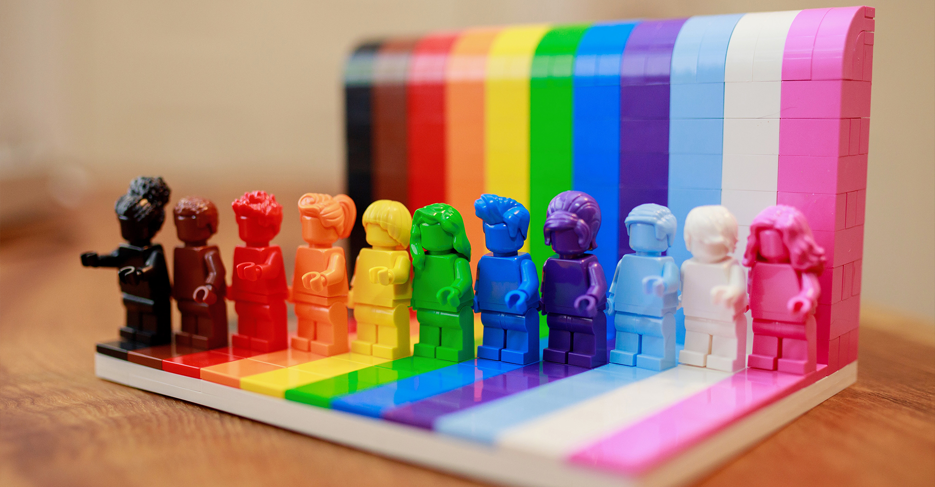 A photographic style image of a rainbow toy with multiple block people in different colours on it.